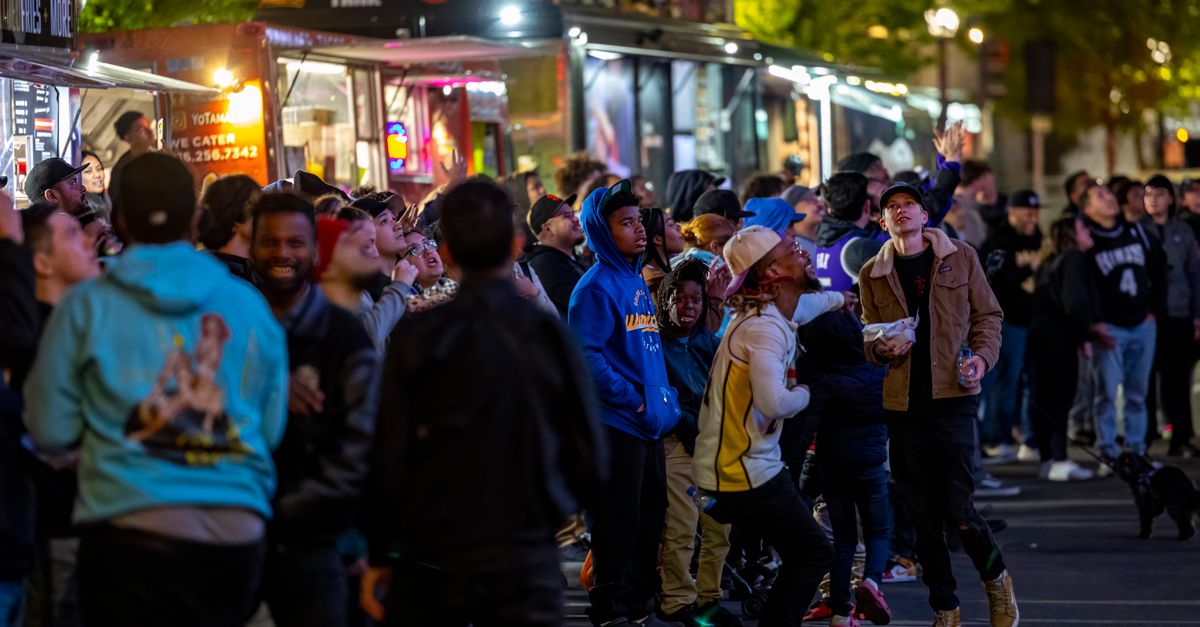 A lively crowd gathers around vibrant food trucks at night, enjoying a bustling street food experience.